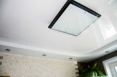 Белый глянцевый потолок с плоской квадратной люстрой